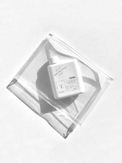 A sleek black bottle of Tenet Nutrition supplement glowing with vibrant orange highlights against a dark, moody background.