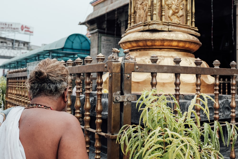 man standing front of golden statue during daytime