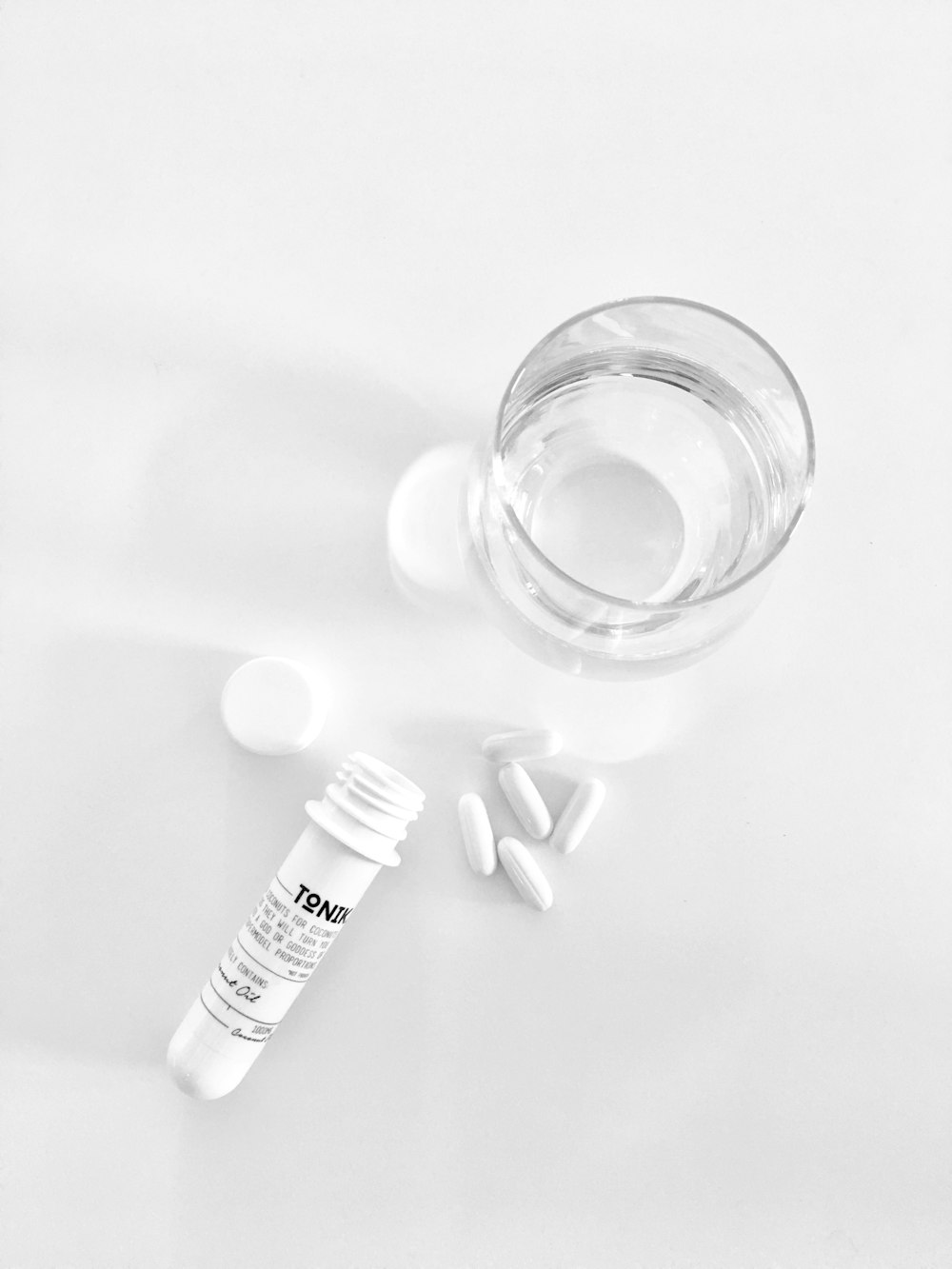 pílulas brancas e um copo de água