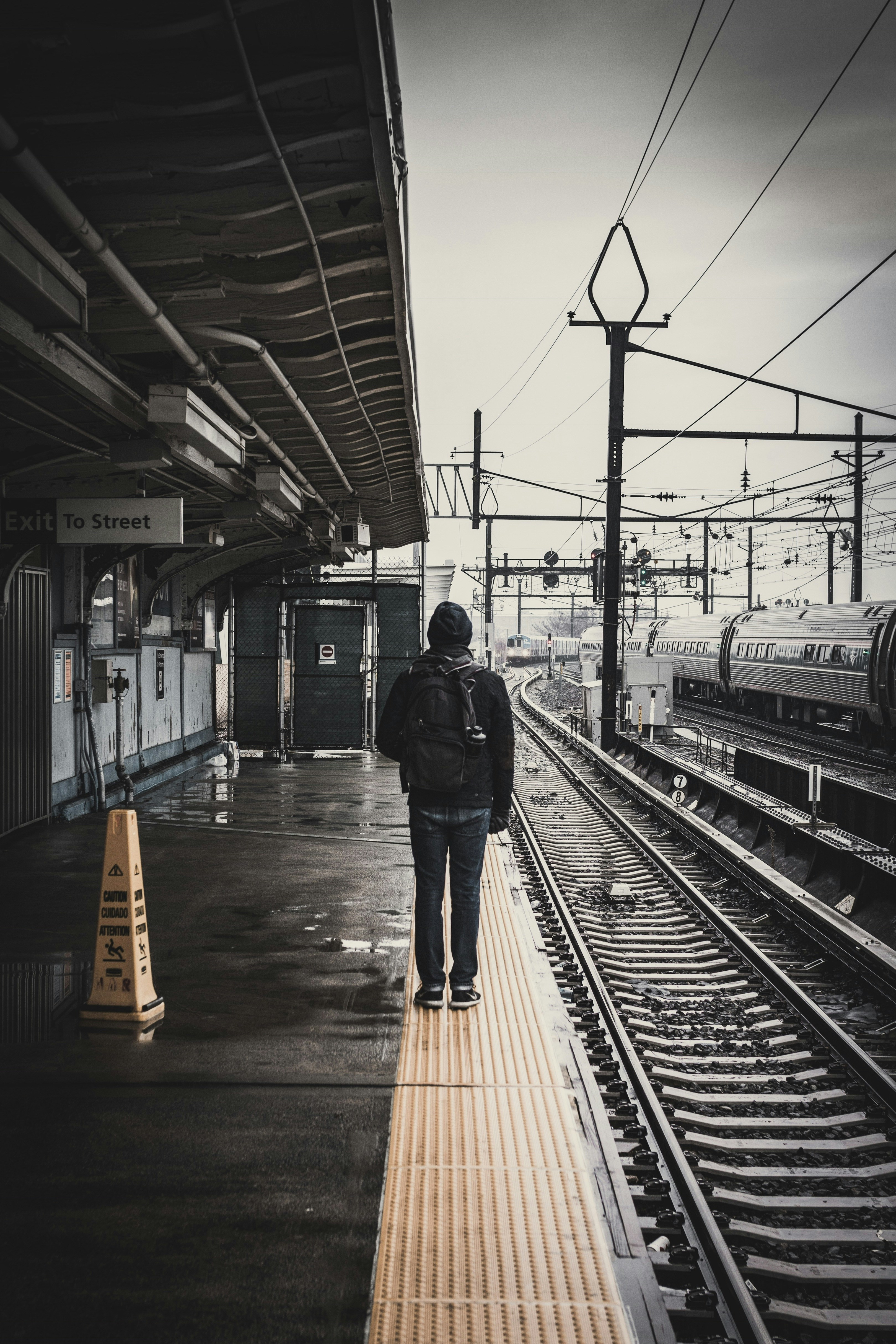 man standing beside train railway
