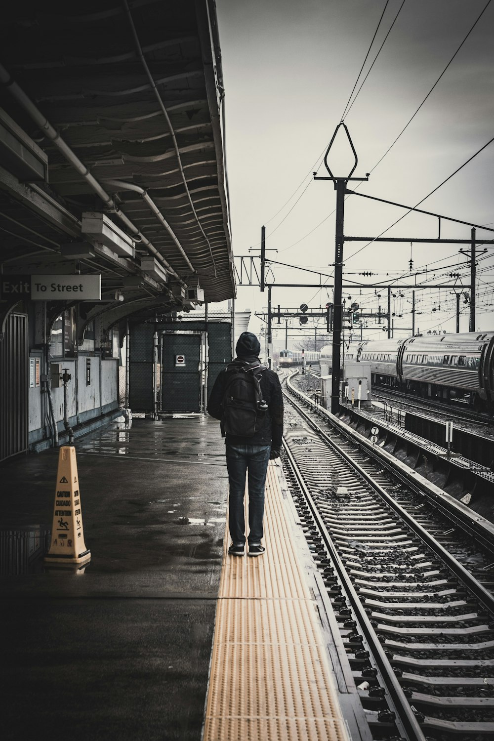 man standing beside train railway