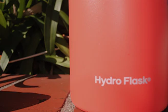 Close-up of a sleek emerald green premium thermos with tactile embossed branding under soft lighting.