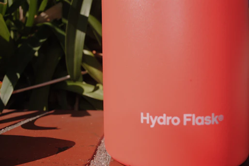 Close-up of a sleek emerald green premium thermos with tactile embossed branding under soft lighting.