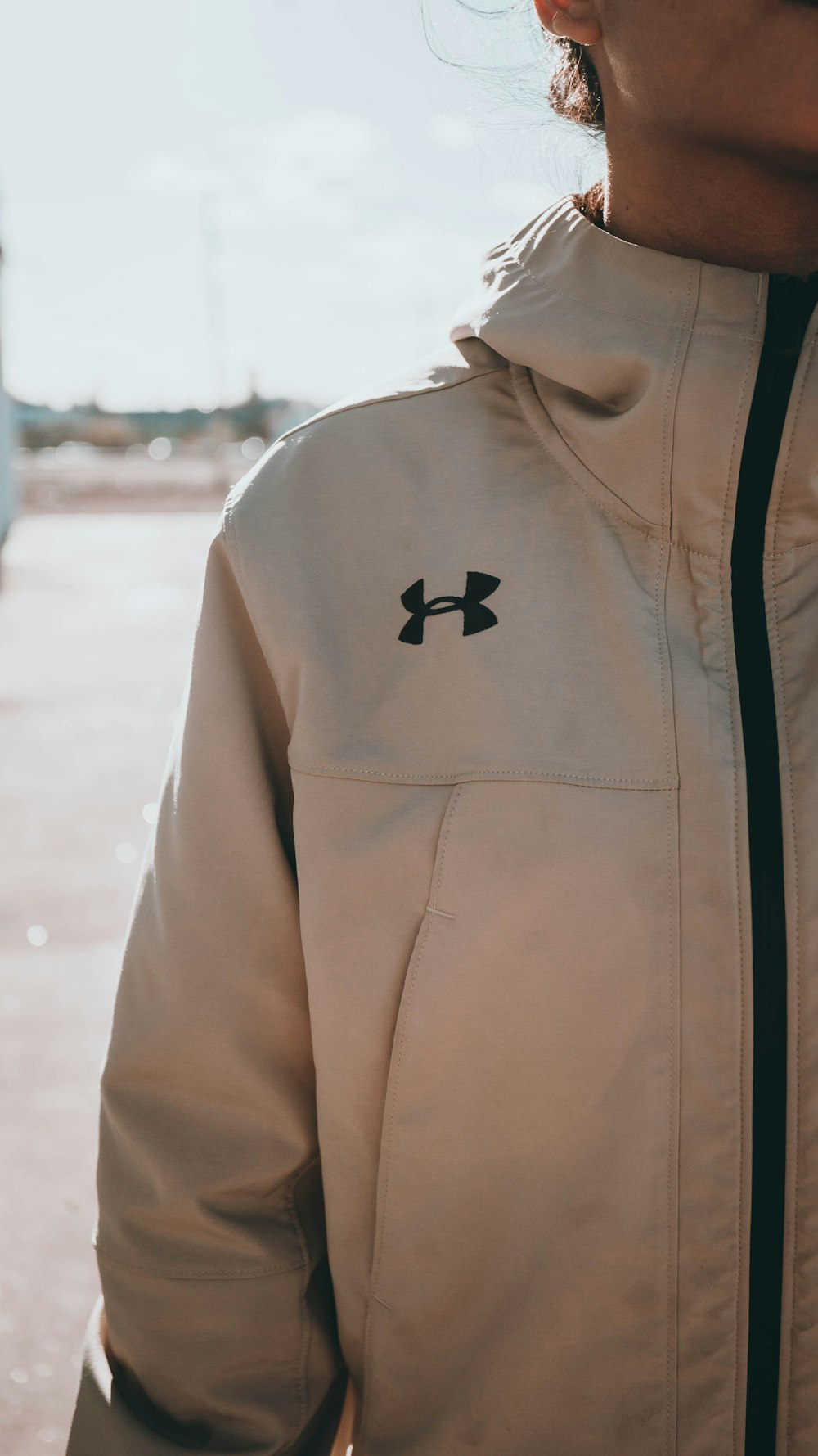 흰색 Under Armour 집업 재킷을 입고 서 있는 여자