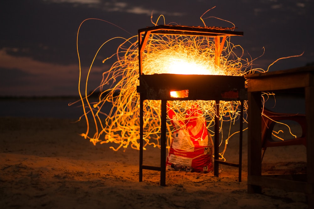 time lapse photography of fire sparking from a grill by the seashore