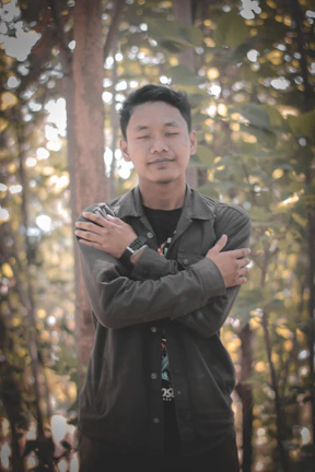 A focused man sitting quietly in meditation, sunlight filtering through a forest.