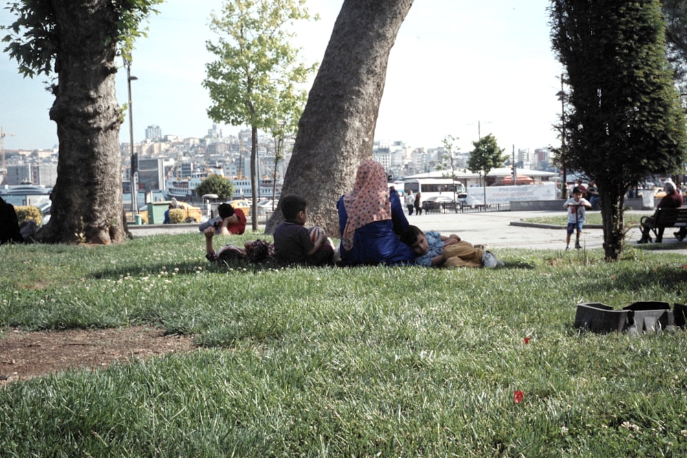 woman and child lying on green grass near tree