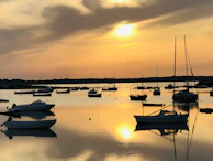Sunset view over a calm lake with diving boats anchored nearby.