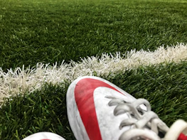 Close-up of football cleats and ball on freshly cut grass.