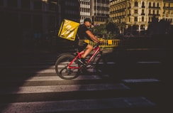A courier on a bicycle delivering eyeglasses in a leafy Bogotá neighborhood.