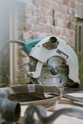 grey and teal Makita miter saw on table outdoors during daytime