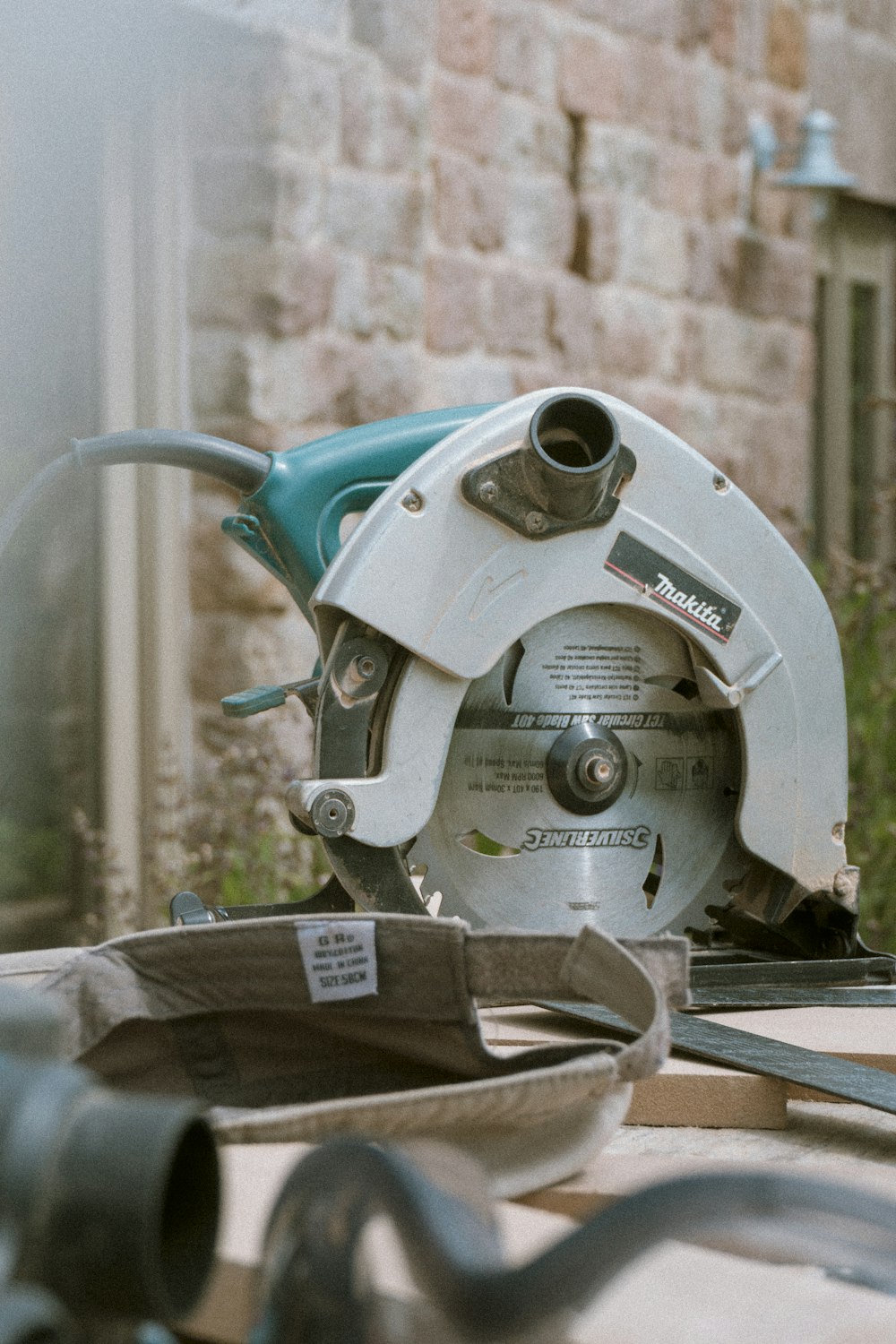 grey and teal Makita miter saw on table outdoors during daytime