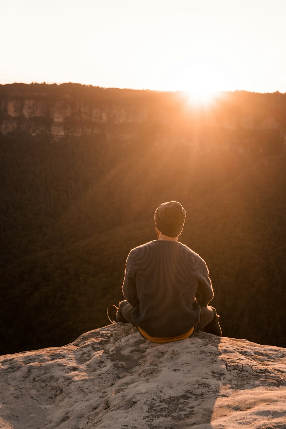 man in bonnet sitting on top of mountain