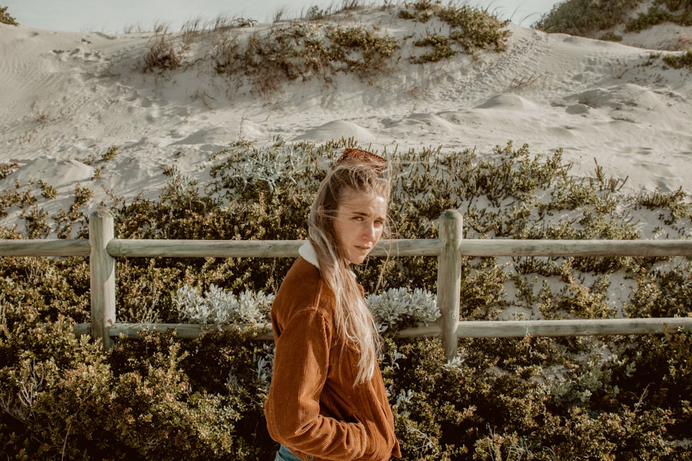 woman in brown jacket standing in beach