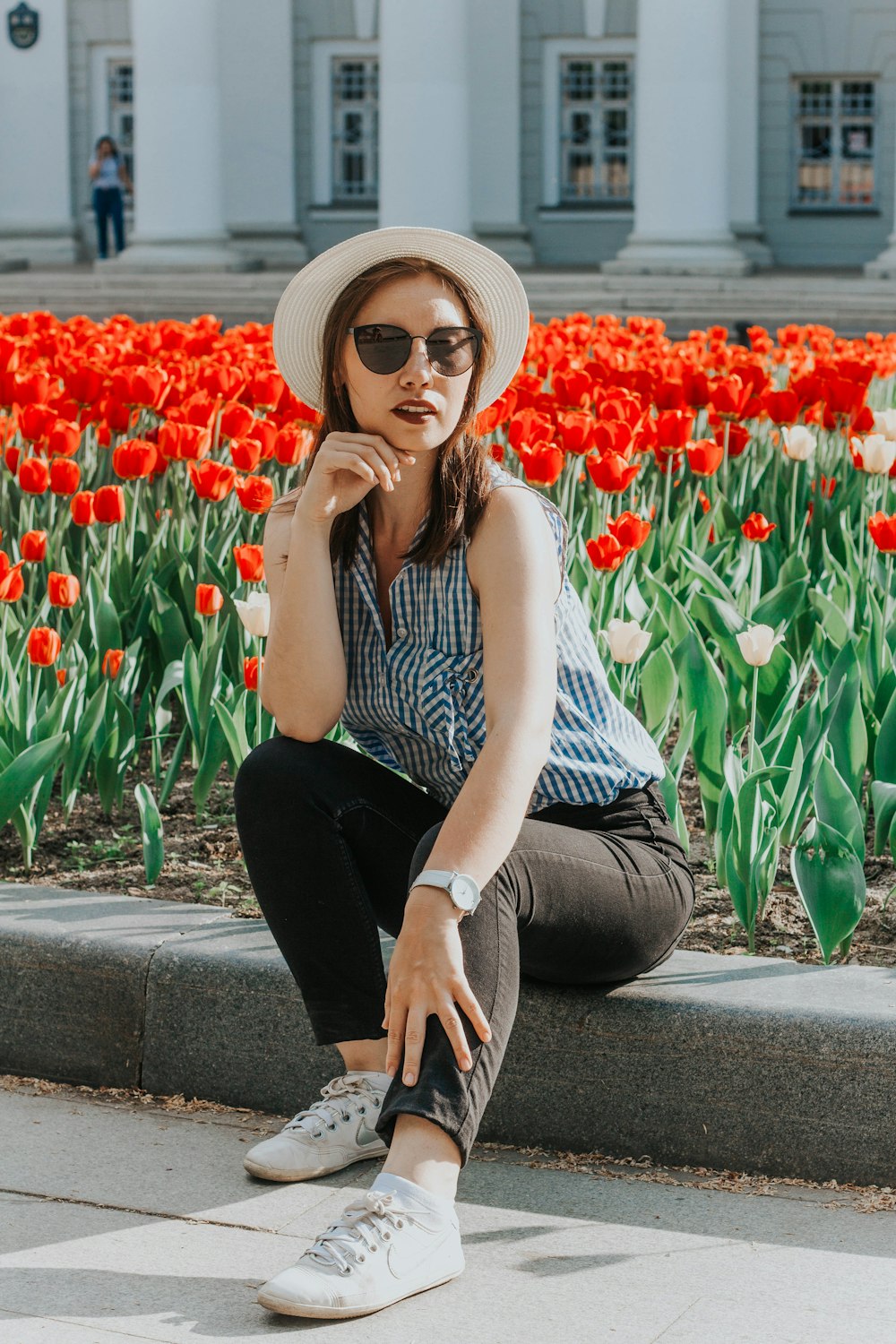 woman sitting beside garden of red tulip flowers