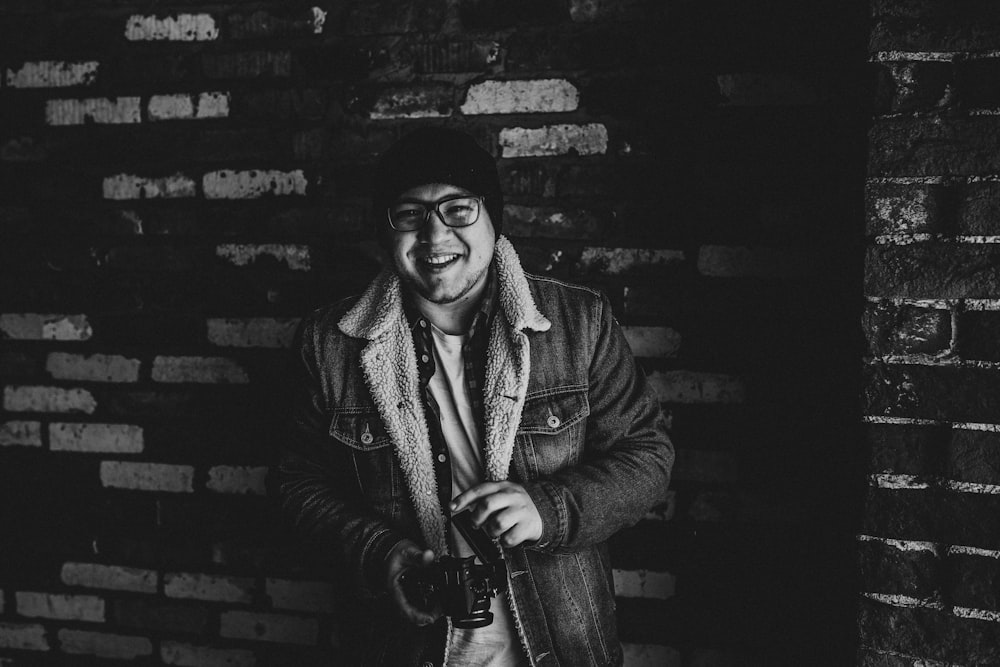 grayscale photography of smiling man carrying camera
