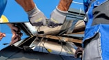 two men carrying a metal sheet