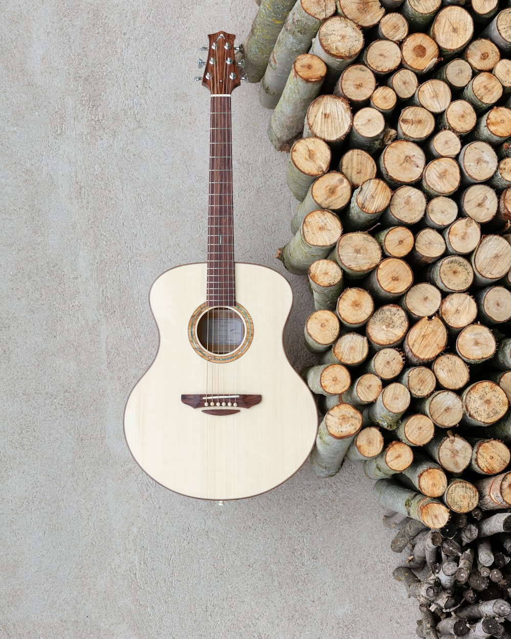 brown acoustic guitar near pile of wood