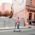 two men riding kick scooters during daytime