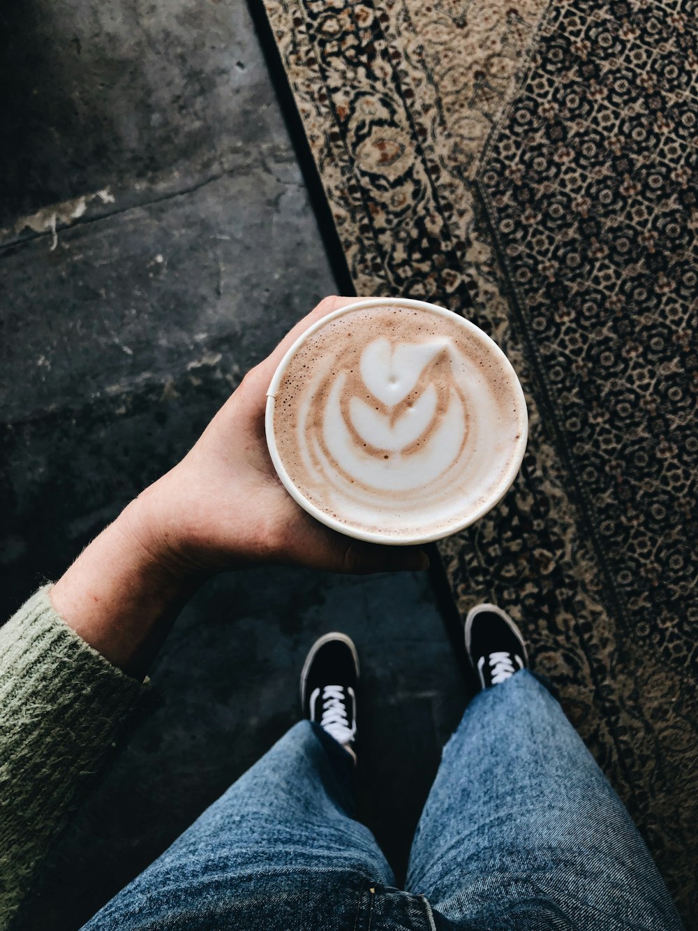 person holding paper cup with latte