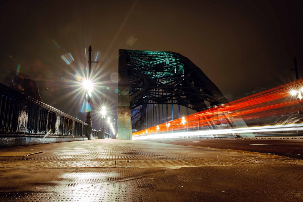 a city street at night with a bridge in the background