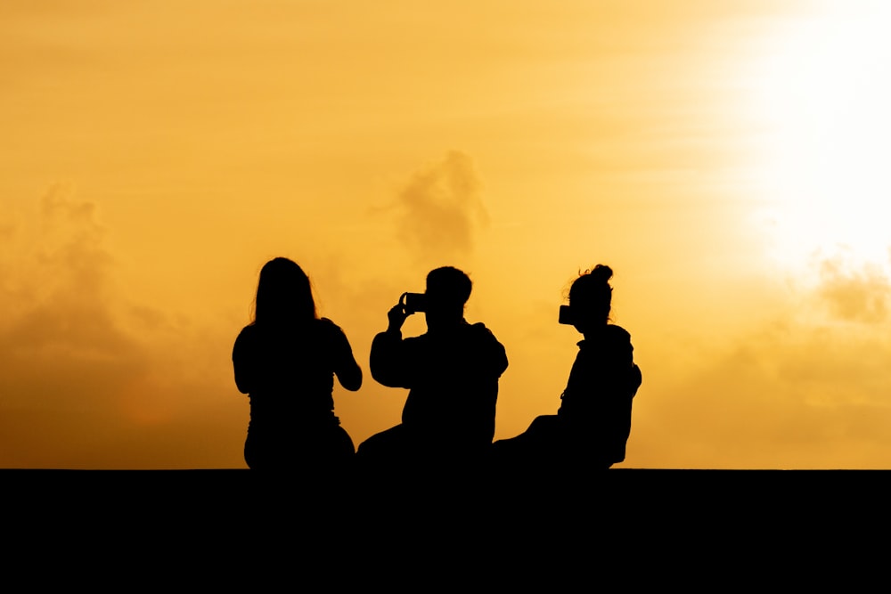 silhouette photography of man sitting beside two women