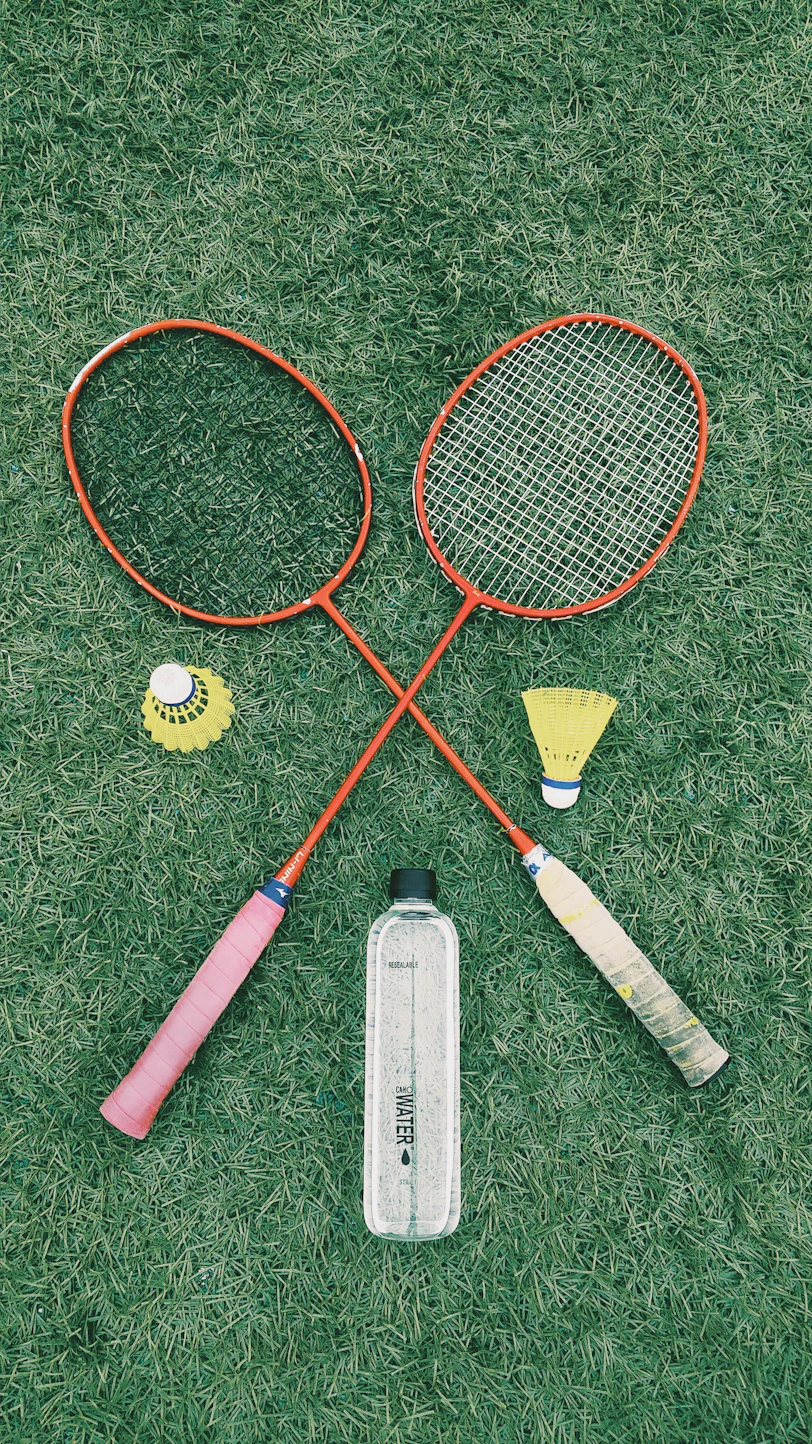 pair of red badminton rackets on the grass