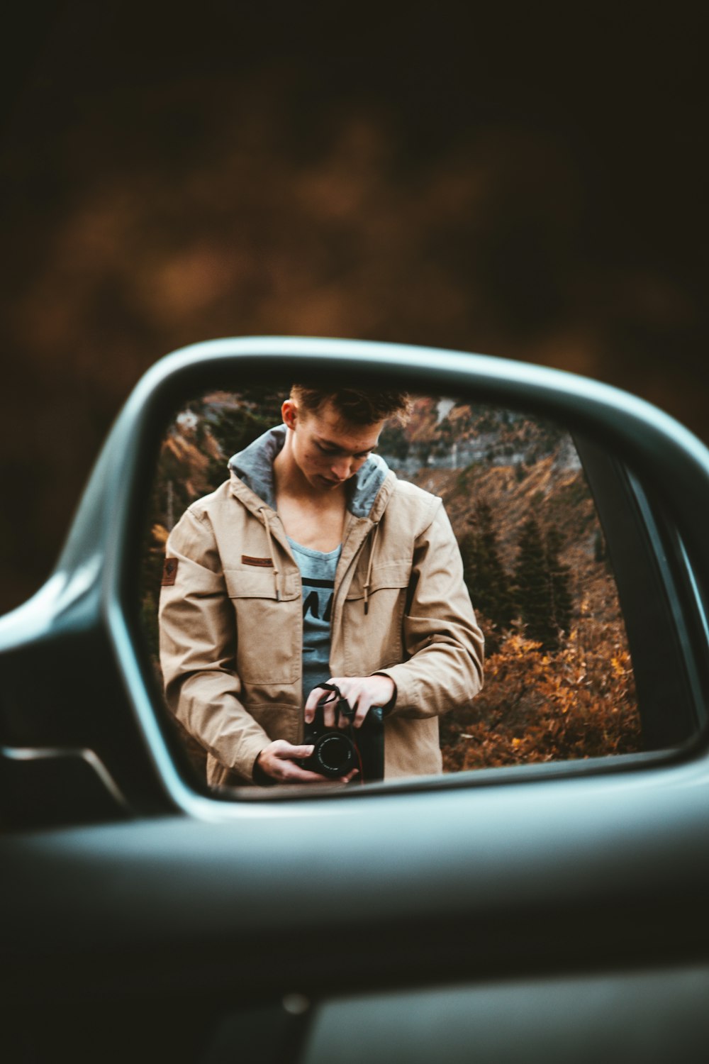 man holding camera reflected in side mirror