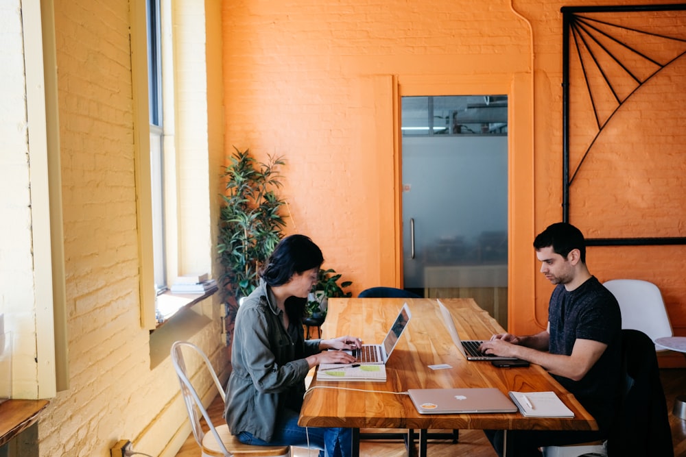 man and woman using laptop on table