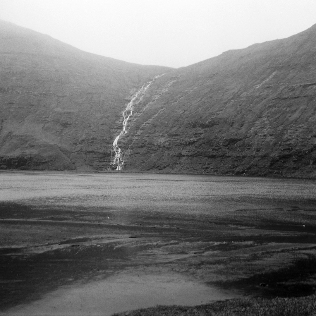 grayscale photography of body of water and hill