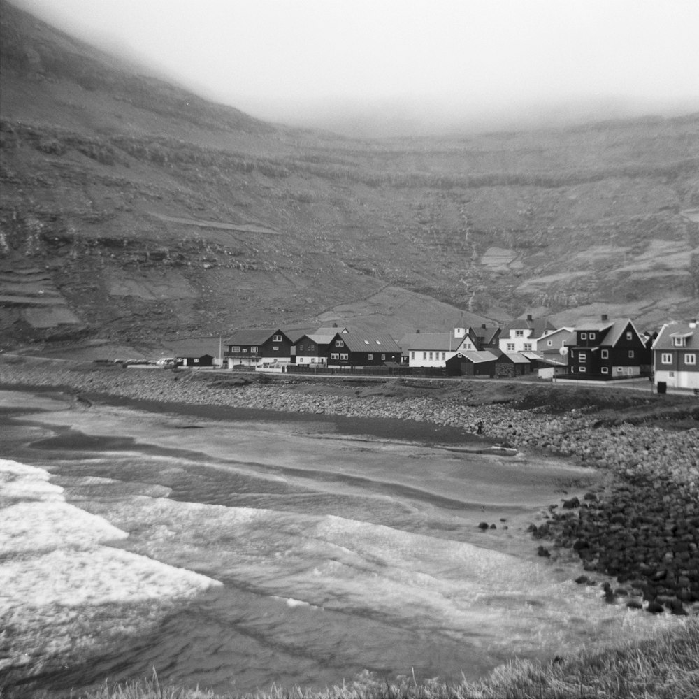 Fotografía en escala de grises de casas cerca del río