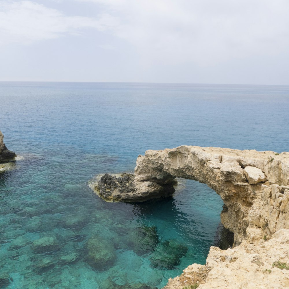 brown rock formation beside blue water