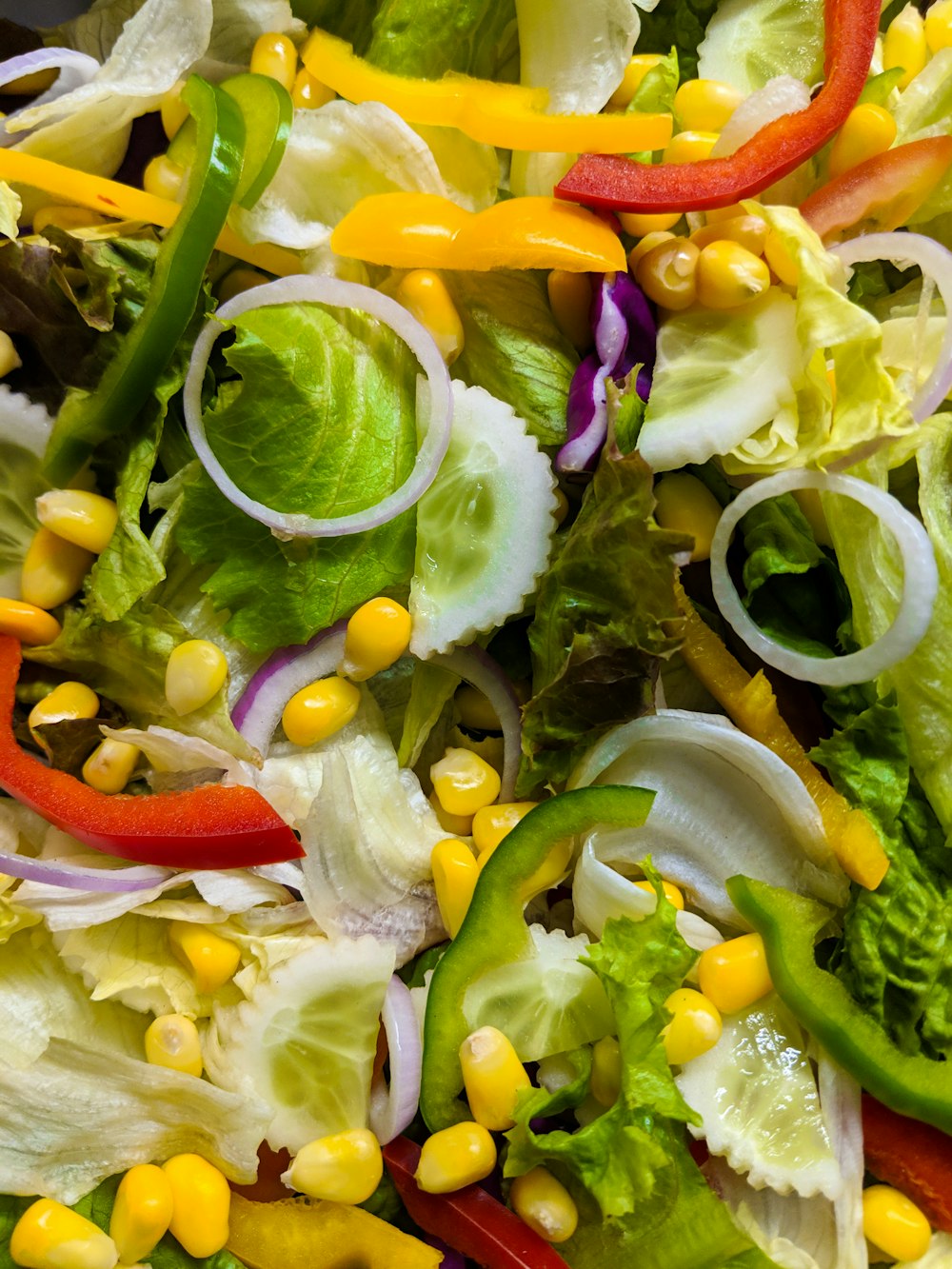a close up of a salad with peppers and corn