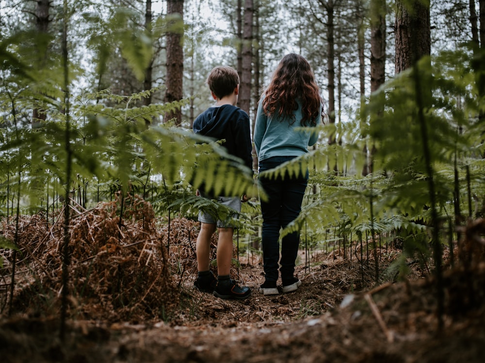 숲에 나란히 서 있는 소녀와 소년