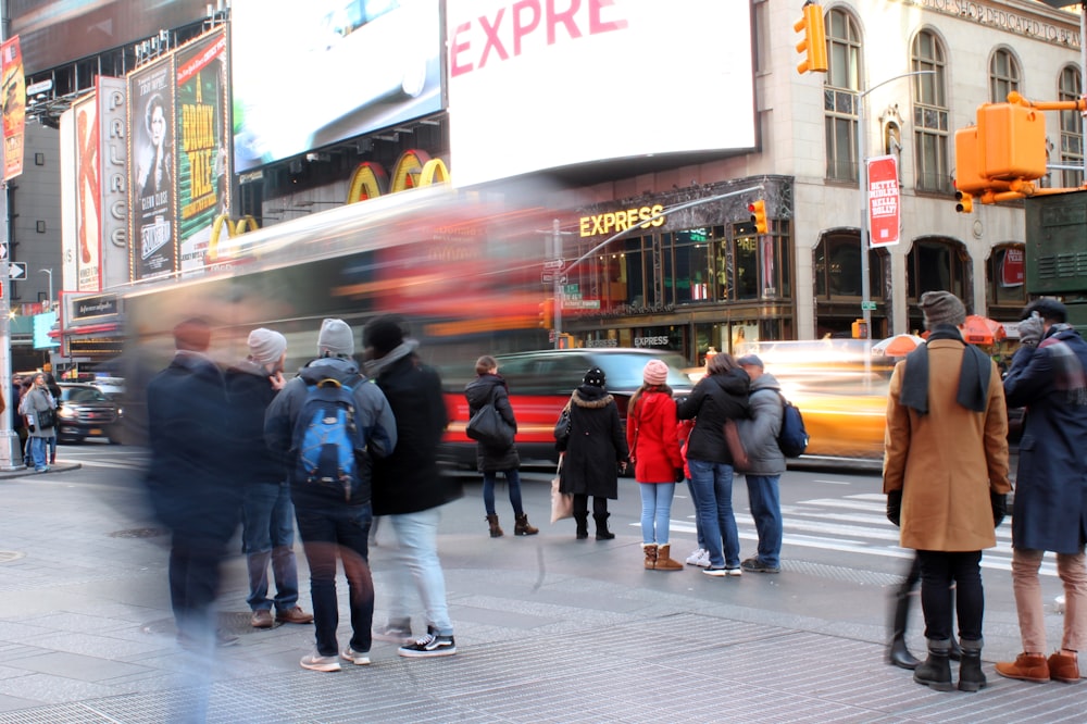 people standing at sidewalk along busy street