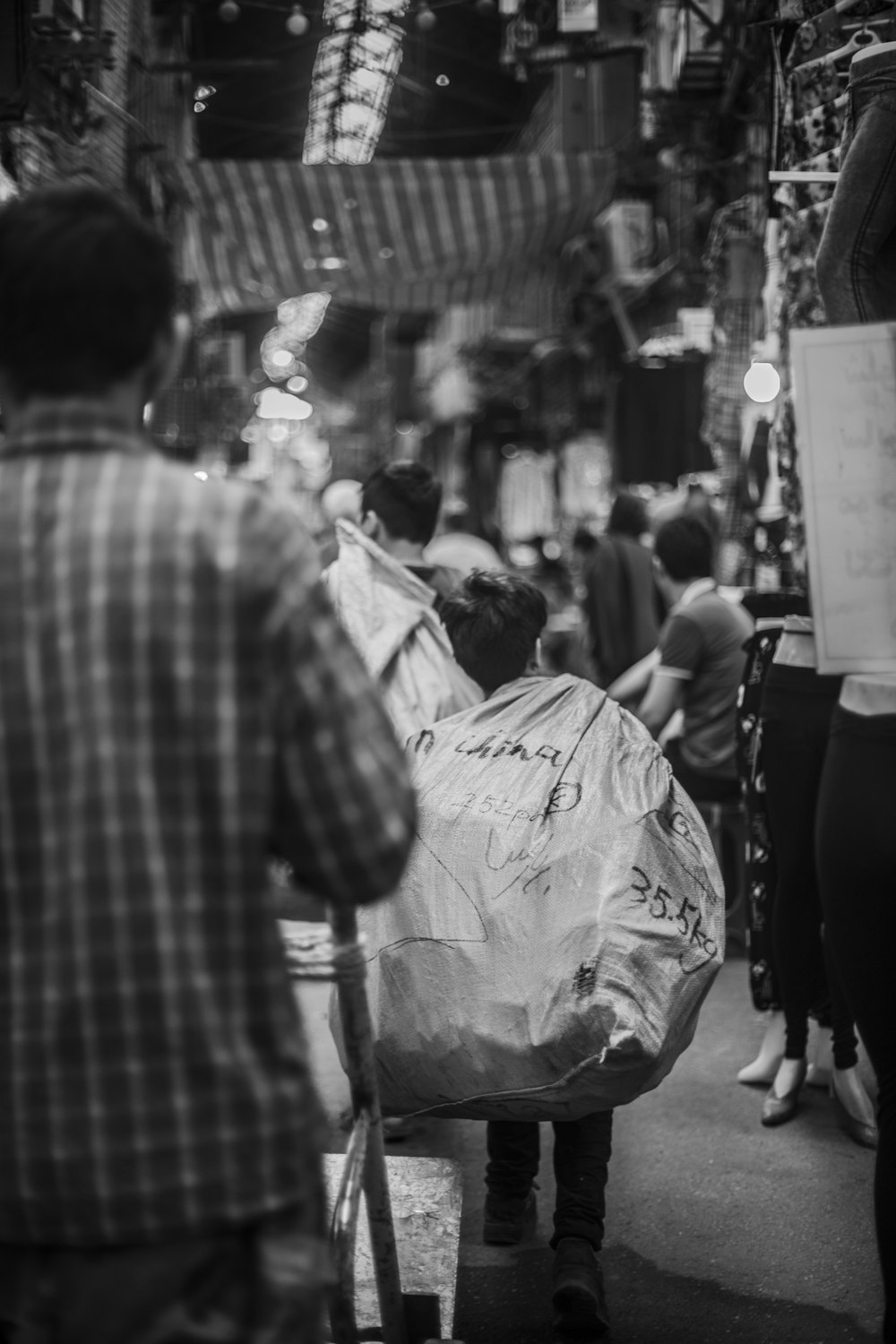 grayscale photography of boy carrying sack while walking