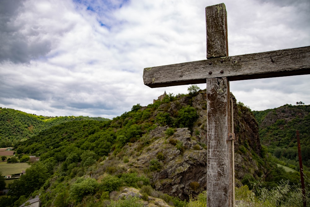 Blick auf den grünen Hügel vom braunen Holzkreuz