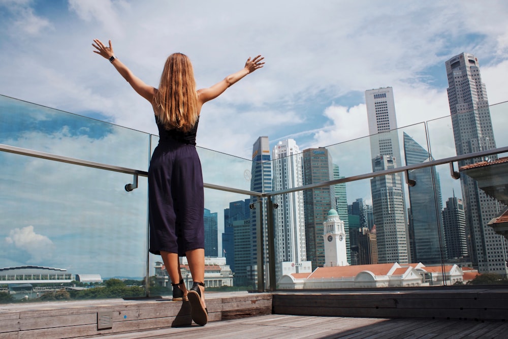 woman raising her hands while standing near glass wall