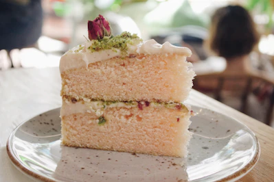 Close-up of an artisanal layered cake with pistachio cream and fresh berries on a rustic wooden table.