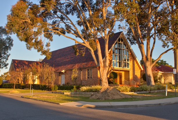 Historic schoolhouse building bathed in warm afternoon light, surrounded by mature trees.