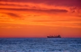 Sunset silhouette of a tanker sailing across the horizon.