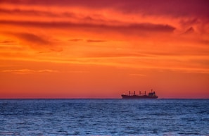 Sunset silhouette of a petroleum tanker cutting through the ocean waves, highlighting the company’s commitment to timely delivery.