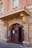 An entrance to a historic brick building featuring a curved archway with the words 'Court House' prominently displayed above a double wooden door. The architecture has ornate elements with a mix of stone and brick textures, and there are windows above the entrance.
