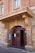 An entrance to a historic brick building featuring a curved archway with the words 'Court House' prominently displayed above a double wooden door. The architecture has ornate elements with a mix of stone and brick textures, and there are windows above the entrance.
