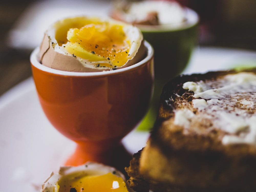 an egg is in a bowl on a plate next to toast