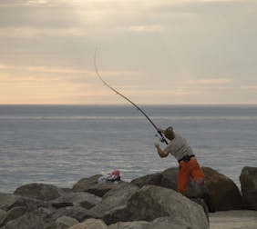 An angler casting a line from a rocky shore at sunrise, showcasing the gear in action.