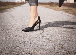 woman standing while wearing black leather heeled sandals