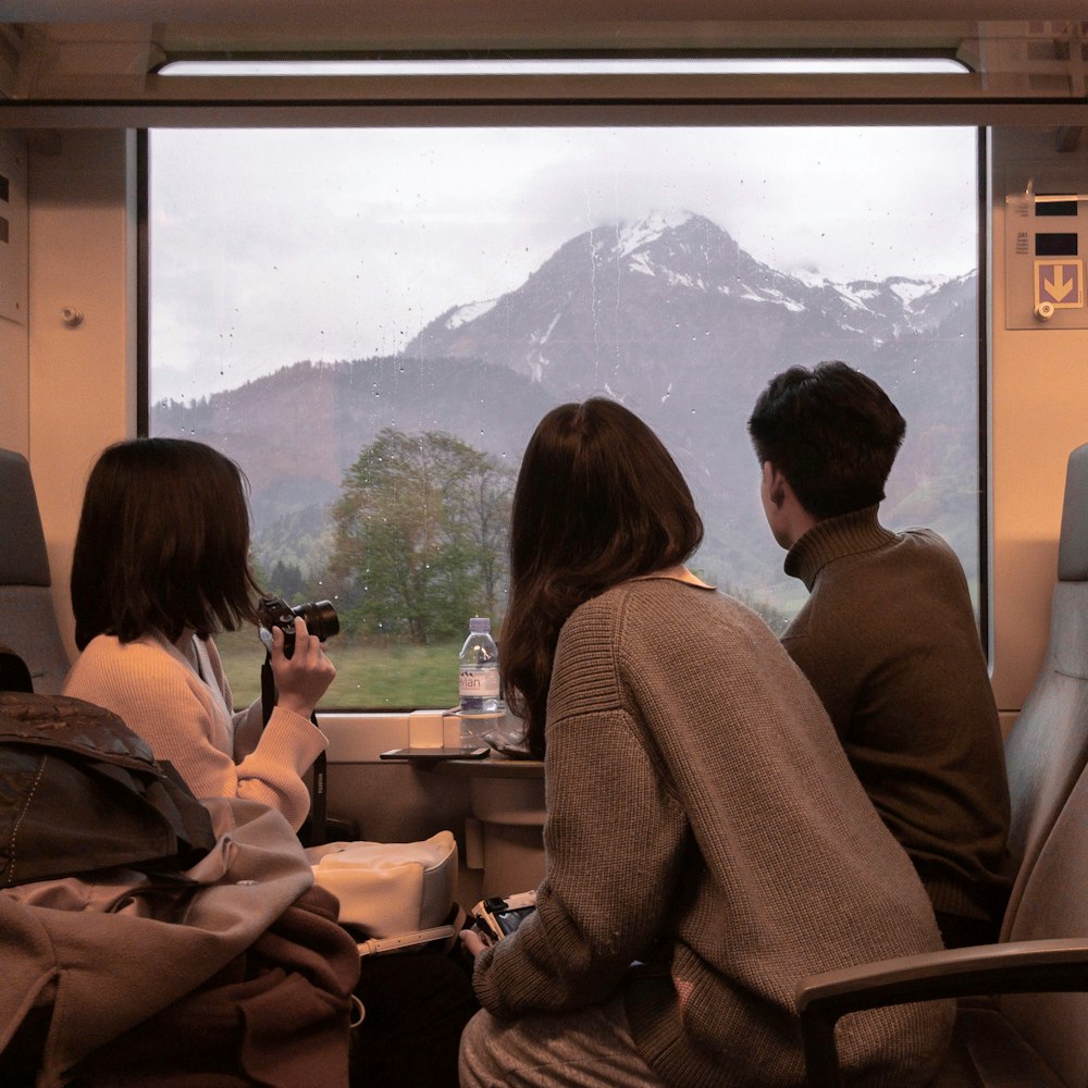 Tres personas sentadas en un tren mirando por la ventana