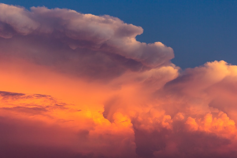 a plane flying through a cloudy sky at sunset