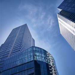 two tall buildings with glass windows against a blue sky